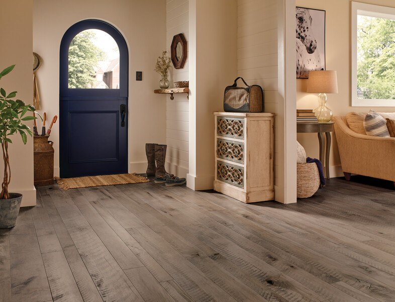 Home entry with a dark, rounded door and small cabinet featuring a linear patterned hardwood floor 