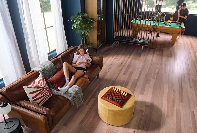 Family room with hardwood flooring and a teenager reading on a couch and two young boys playing pool in the adjacent space