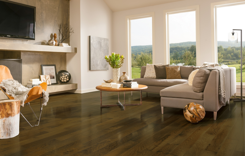 Dark hardwood floors in a living room with picture windows overlooking the outdoors